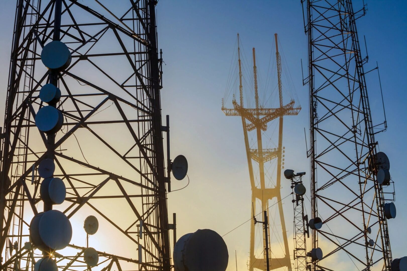 A group of towers with antennas in the background.